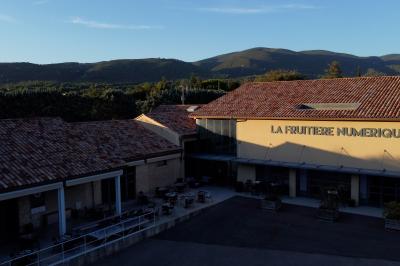 Salle de réunion avec tables et chaises disposées en U, grand écran blanc, plantes et buffet en arrière-plan.
