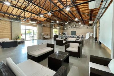 Salle de réunion avec tables et chaises disposées en U, grand écran blanc, plantes et buffet en arrière-plan.