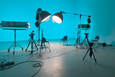 Salle de réunion avec tables et chaises disposées en U, grand écran blanc, plantes et buffet en arrière-plan.