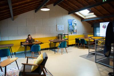 Salle de réunion avec tables et chaises disposées en U, grand écran blanc, plantes et buffet en arrière-plan.