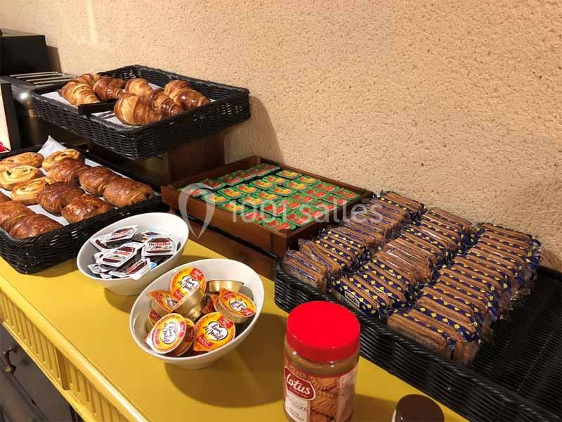 Buffet avec viennoiseries, confitures, pâte à tartiner, biscuits emballés et portions individuelles de beurre.