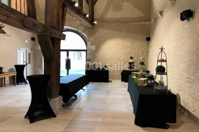 Un vase de fleurs sur une table en bois dans une salle avec poutres apparentes, un panneau ’Bienvenue’ au premier plan.