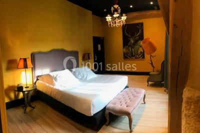 Un vase de fleurs sur une table en bois dans une salle avec poutres apparentes, un panneau ’Bienvenue’ au premier plan.