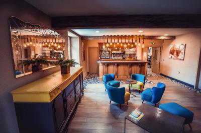 Un vase de fleurs sur une table en bois dans une salle avec poutres apparentes, un panneau ’Bienvenue’ au premier plan.