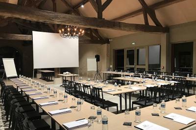 Un vase de fleurs sur une table en bois dans une salle avec poutres apparentes, un panneau ’Bienvenue’ au premier plan.