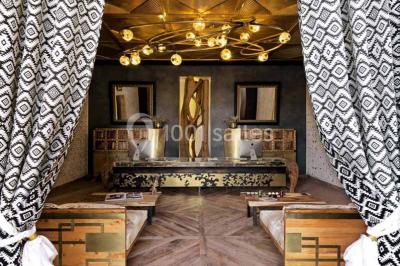 Cloison décorative ajourée en bois sombre devant une baignoire avec robinetterie métallique, lumière naturelle en arrière…