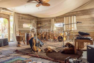 Cloison décorative ajourée en bois sombre devant une baignoire avec robinetterie métallique, lumière naturelle en arrière…