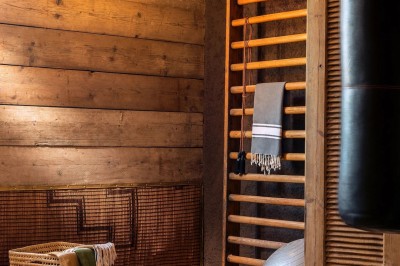 Cloison décorative ajourée en bois sombre devant une baignoire avec robinetterie métallique, lumière naturelle en arrière…