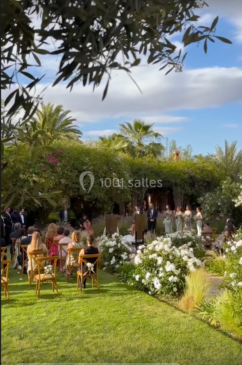 Cérémonie de mariage en plein air dans un jardin verdoyant, entourée de fleurs blanches et d'invités assis.
