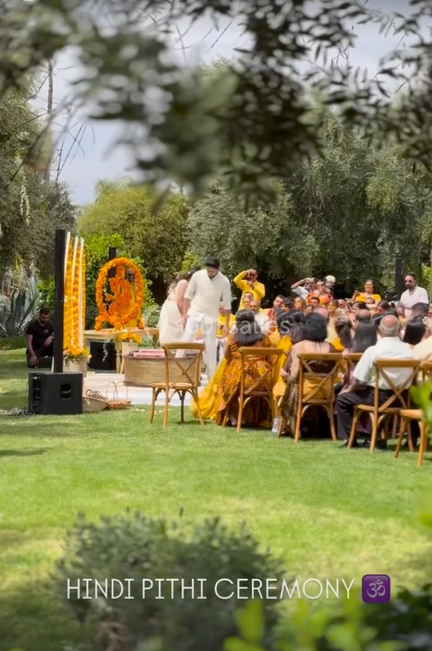 Un couple participe à une cérémonie hindoue en plein air, entouré d'invités assis et de décorations traditionnelles.