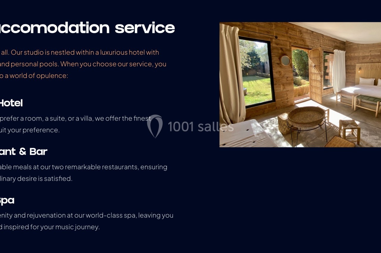 Vue d'une chambre d'hôtel lumineuse en bois avec un lit, un coin salon, de grandes fenêtres et une vue sur un jardin.