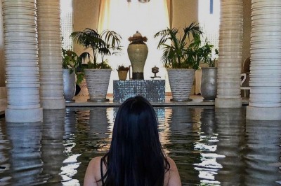 Cloison décorative ajourée en bois sombre devant une baignoire avec robinetterie métallique, lumière naturelle en arrière…