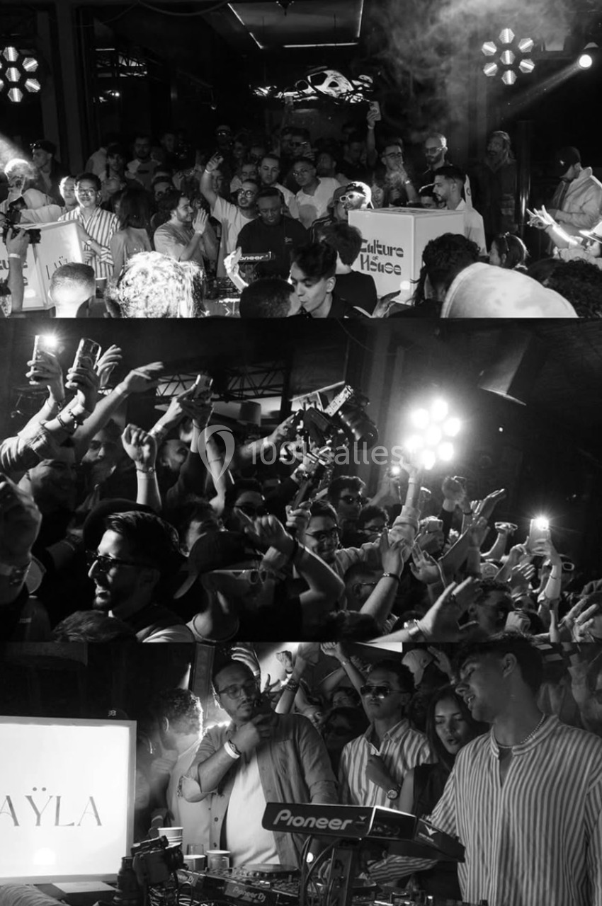 Foule dansant dans un club avec un DJ aux platines, éclairage lumineux et ambiance festive.