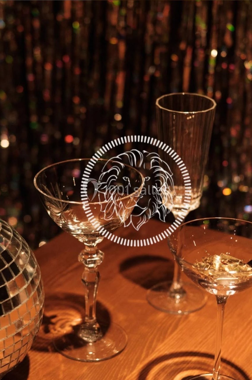 Verres à cocktail vides sur une table en bois, avec une boule à facettes et un fond scintillant.