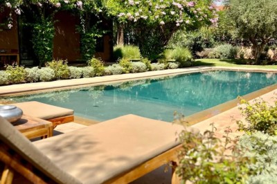 Cloison décorative ajourée en bois sombre devant une baignoire avec robinetterie métallique, lumière naturelle en arrière…