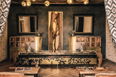 Cloison décorative ajourée en bois sombre devant une baignoire avec robinetterie métallique, lumière naturelle en arrière…