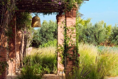 Cloison décorative ajourée en bois sombre devant une baignoire avec robinetterie métallique, lumière naturelle en arrière…