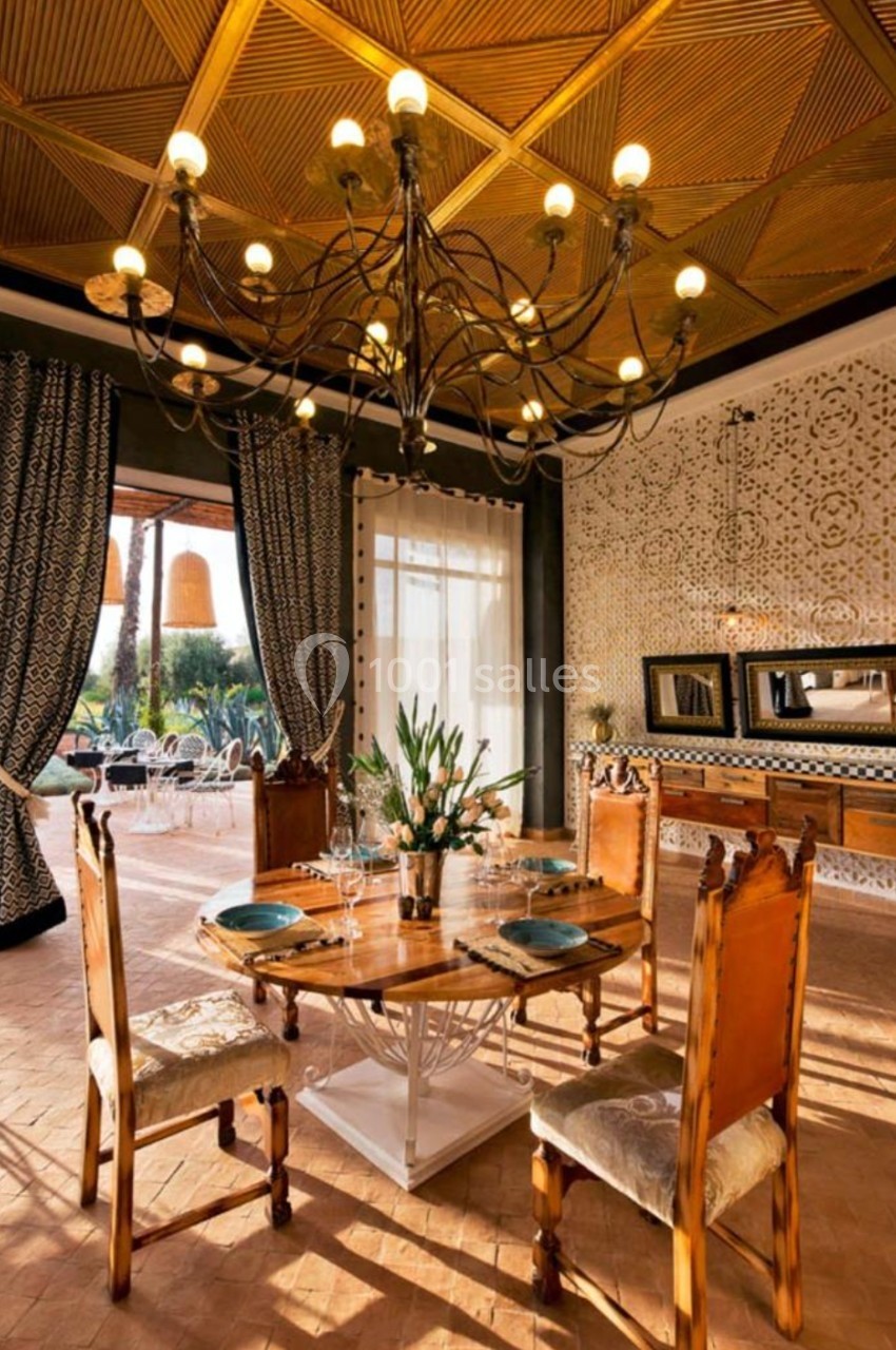 Salle à manger élégante avec table en bois, chaises sculptées, lustre imposant et décorations murales raffinées.