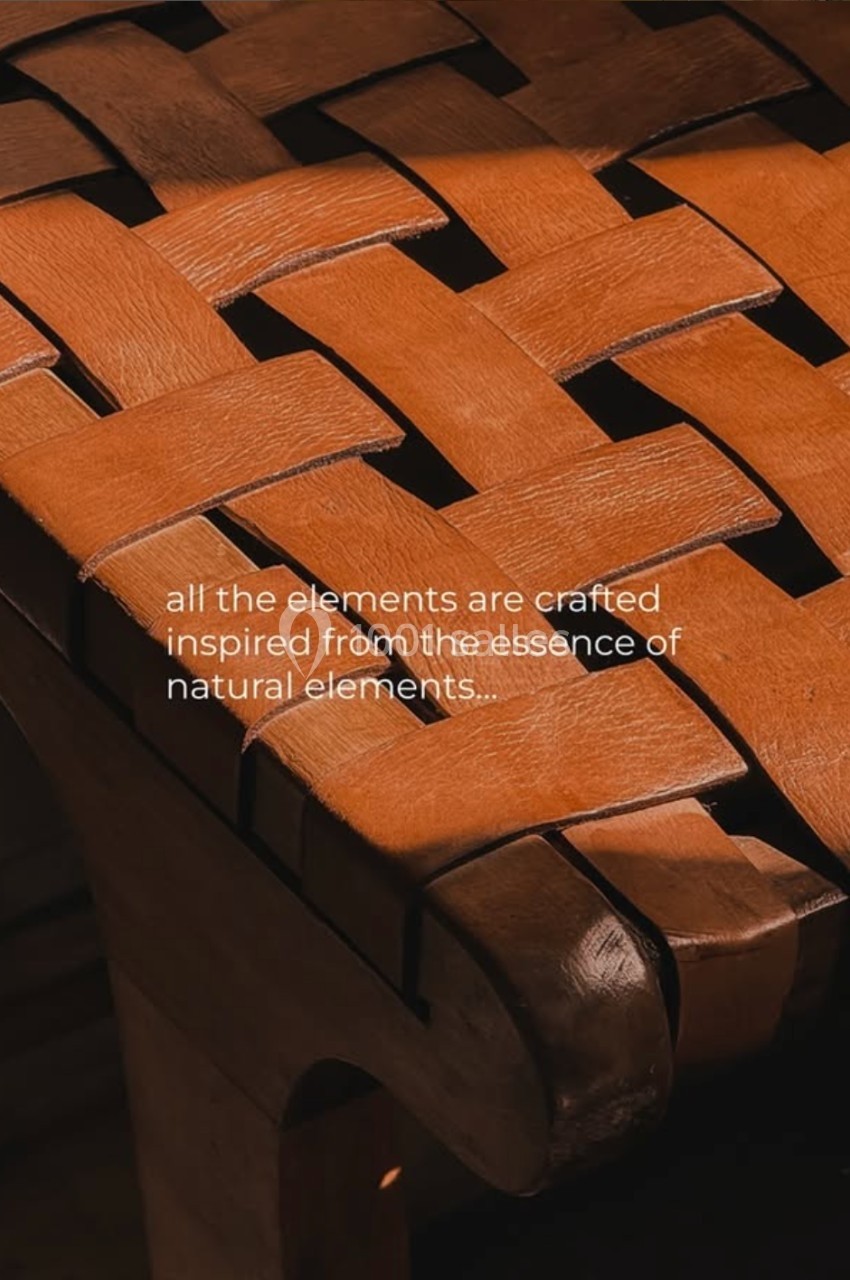 Chaise en bois avec assise tressée en lanières de cuir, éclairée par une lumière chaude.