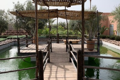 Cloison décorative ajourée en bois sombre devant une baignoire avec robinetterie métallique, lumière naturelle en arrière…