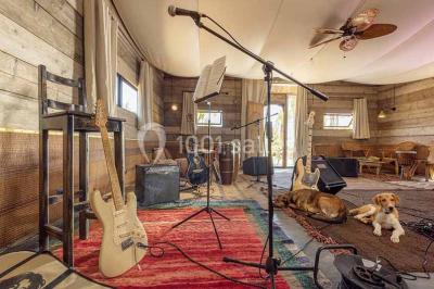 Cloison décorative ajourée en bois sombre devant une baignoire avec robinetterie métallique, lumière naturelle en arrière…