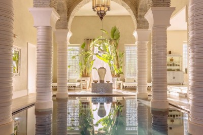 Cloison décorative ajourée en bois sombre devant une baignoire avec robinetterie métallique, lumière naturelle en arrière…