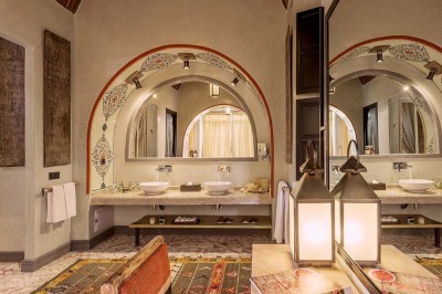 Cloison décorative ajourée en bois sombre devant une baignoire avec robinetterie métallique, lumière naturelle en arrière…