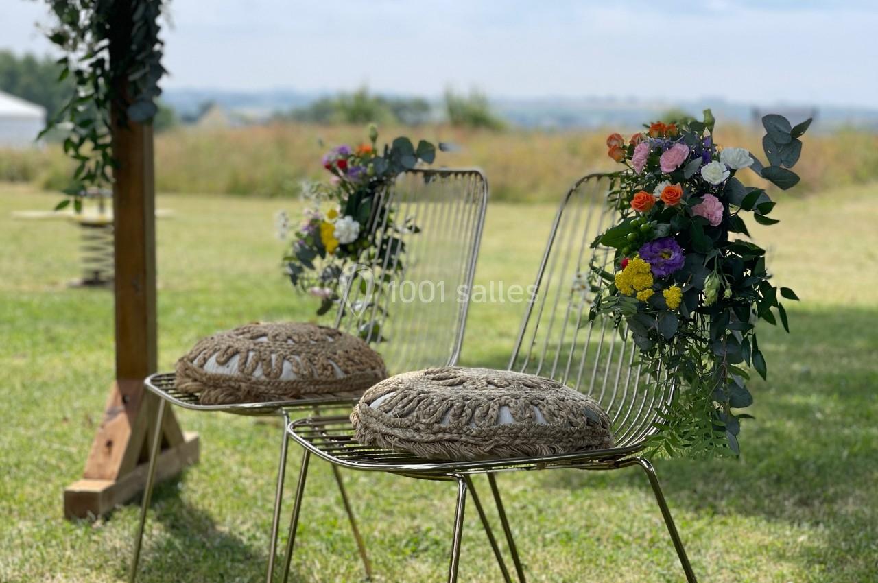 Deux chaises en métal décorées de fleurs colorées, placées sur une pelouse en extérieur par temps clair.