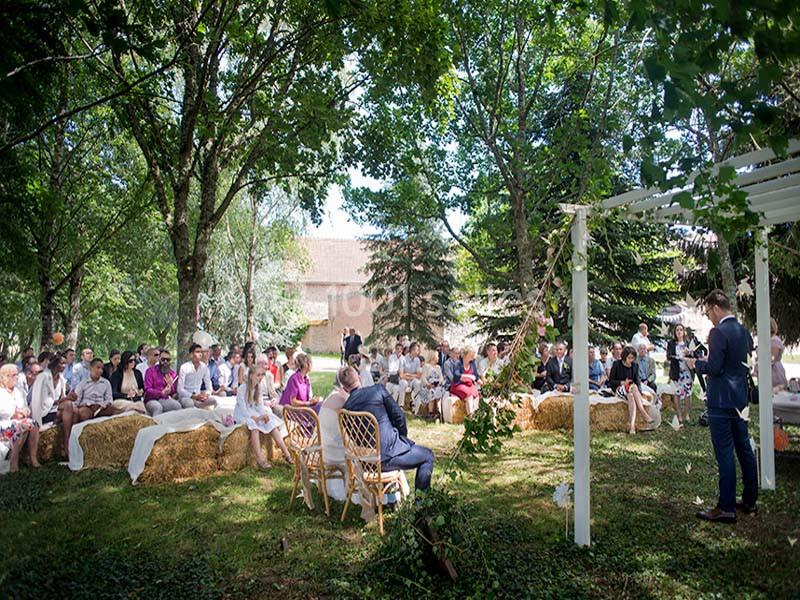 Un groupe de personnes assises en plein air sous des arbres lors d'une cérémonie ou d'un événement.