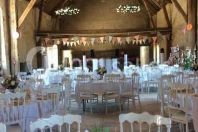 Tables décorées pour un événement avec chandeliers, compositions florales suspendues et lumière tamisée.