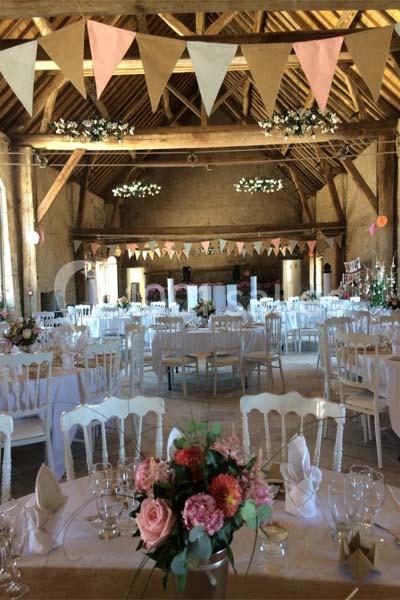 Salle de réception décorée avec des guirlandes de fanions, des tables dressées et des compositions florales.