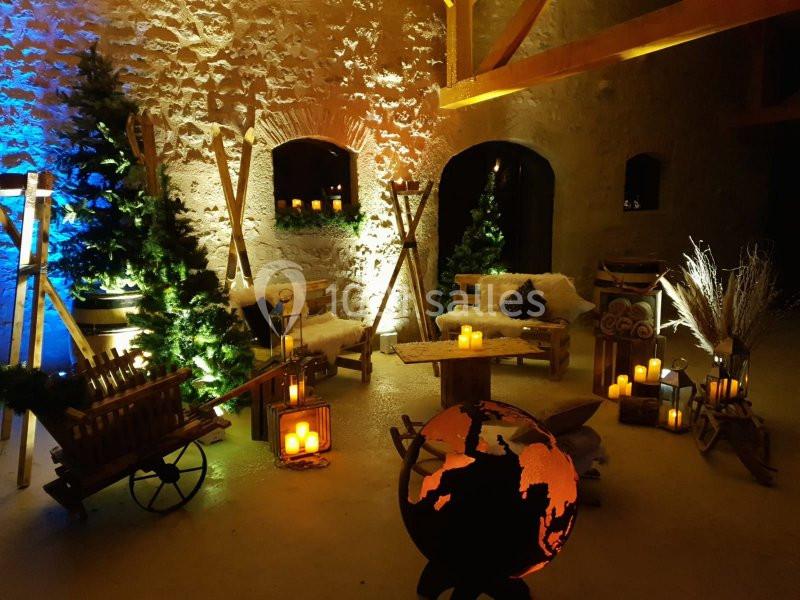 Décoration chaleureuse avec bougies, sapins, fauteuils en bois et globe lumineux dans une ambiance rustique.