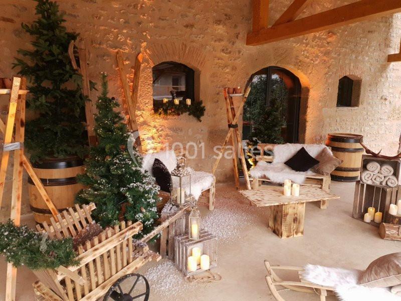 Espace décoré avec des sapins, bougies, fauteuils en bois et pierres apparentes dans une ambiance chaleureuse.