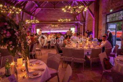 Tables décorées pour un événement avec chandeliers, compositions florales suspendues et lumière tamisée.