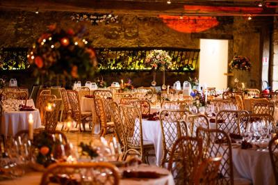 Tables décorées pour un événement avec chandeliers, compositions florales suspendues et lumière tamisée.