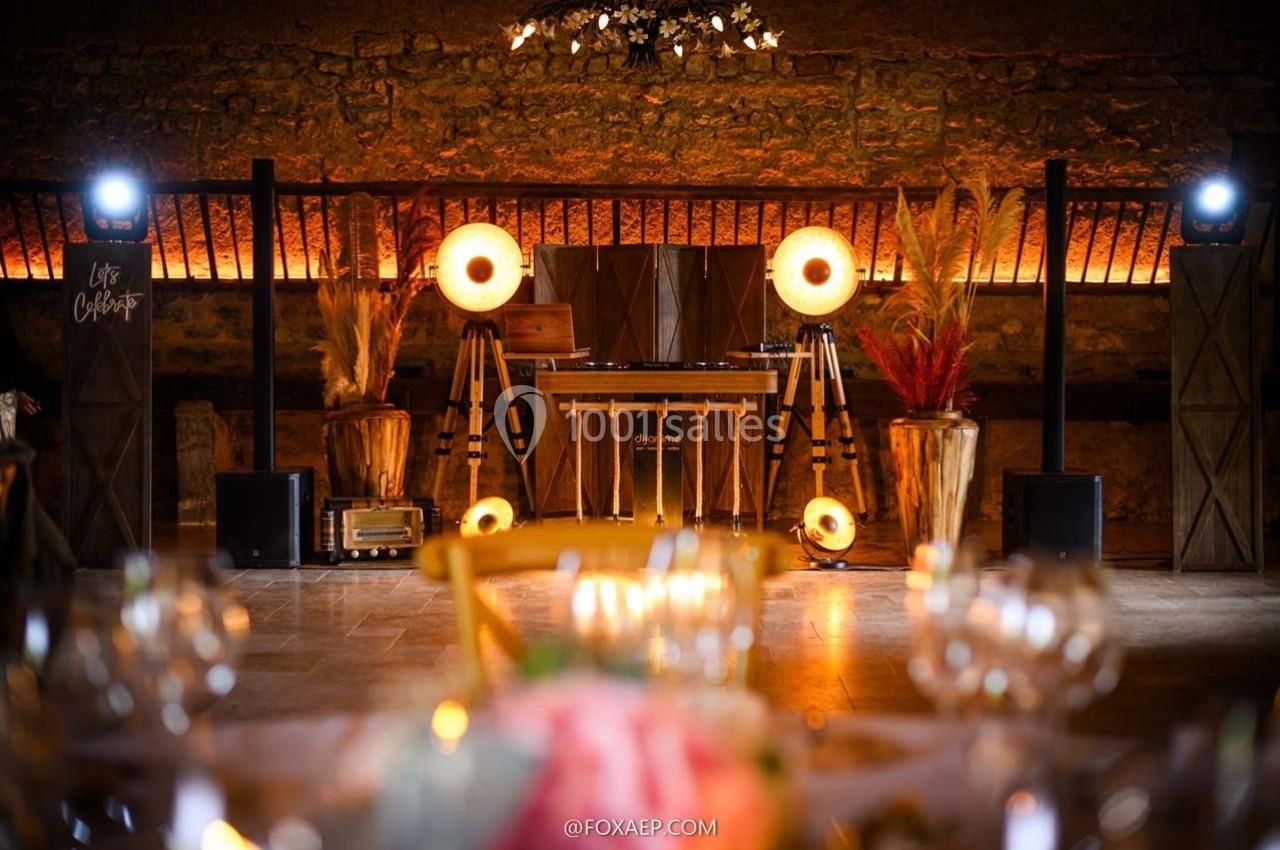 Installation de DJ avec éclairage chaleureux, décor rustique et plantes séchées dans une salle en pierre.