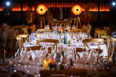 Tables décorées pour un événement avec chandeliers, compositions florales suspendues et lumière tamisée.