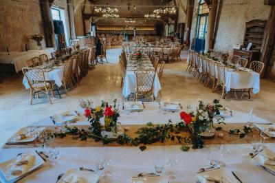 Tables décorées pour un événement avec chandeliers, compositions florales suspendues et lumière tamisée.