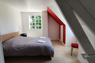 Chambre lumineuse avec lit double, draps bleus, moustiquaire suspendue et éclairage doux.