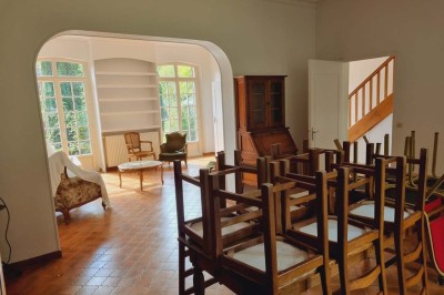 Salle de réception décorée avec des tables rondes, nappes blanches, chaises blanches et centres de table fleuris.