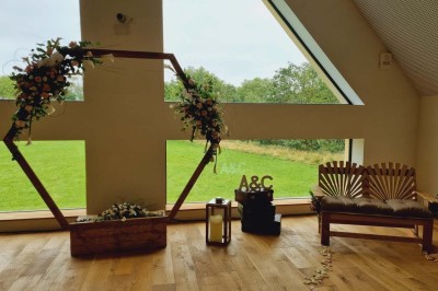 Salle de réception décorée avec des tables rondes, nappes blanches, chaises blanches et centres de table fleuris.