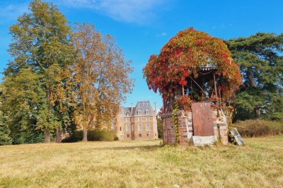 Salle de réception décorée avec des tables rondes, nappes blanches, chaises blanches et centres de table fleuris.