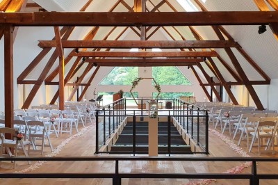 Salle de réception décorée avec des tables rondes, nappes blanches, chaises blanches et centres de table fleuris.