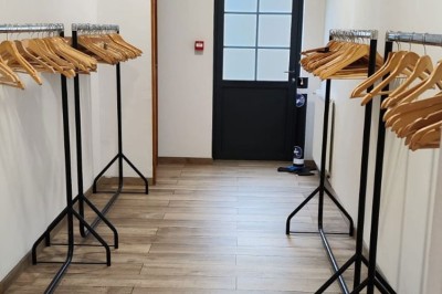 Salle de réception décorée avec des tables rondes, nappes blanches, chaises blanches et centres de table fleuris.