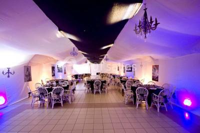 Table de candy bar décorée avec des bonbons variés, lanternes suspendues et éclairage violet en arrière-plan.