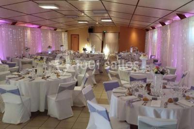 Table de candy bar décorée avec des bonbons variés, lanternes suspendues et éclairage violet en arrière-plan.