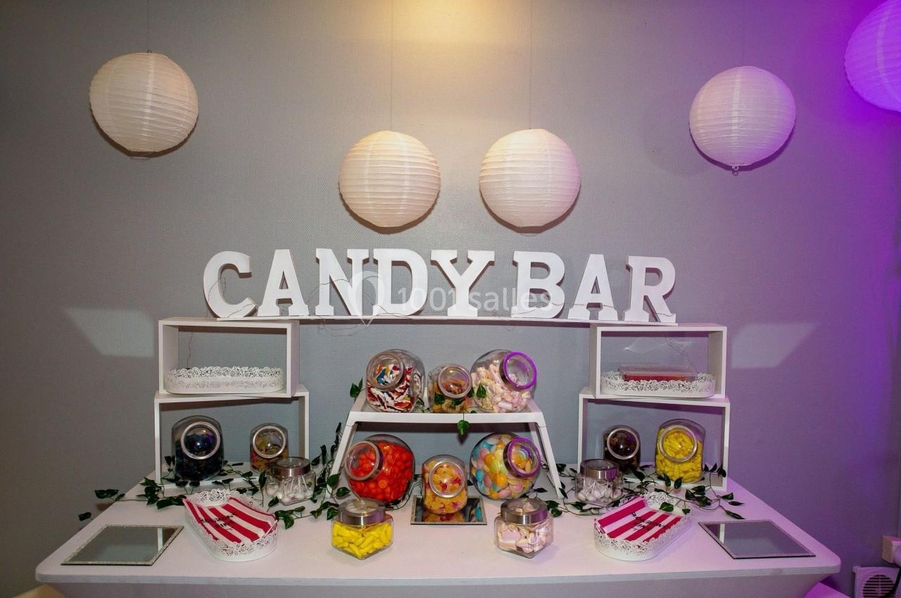 Table de candy bar décorée avec des bonbonnières remplies de sucreries colorées et des lanternes suspendues.