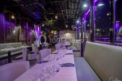 Bar moderne avec comptoir éclairé, bouteilles en arrière-plan, trois verres et une bouteille de champagne au premier plan.