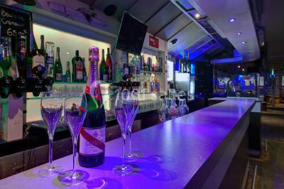 Bar moderne avec comptoir éclairé, bouteilles en arrière-plan, trois verres et une bouteille de champagne au premier plan.