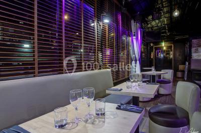 Bar moderne avec comptoir éclairé, bouteilles en arrière-plan, trois verres et une bouteille de champagne au premier plan.